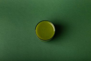 Bir bardak sağlıklı meyve suyu. Yeşil arka planda ananas, kivi, ıspanak ve muzdan yapılmış bir bardak smoothie.. 