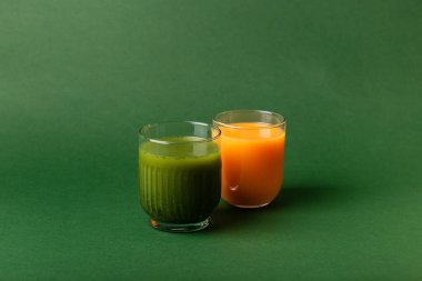 Sağlıklı meyve suyu bardakları. Yeşil zemin üzerinde ananas, kivi, ıspanak ve muzdan yapılmış bir bardak smoothie. Mango, şeftali, kayısı ve havuçtan yapılmış bir bardak smoothie..