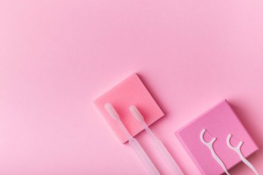 Beyaz diş fırçaları, pembe arka planda diş ipi. Ağız bakımı, sakız ve diş sağlığı. Sabah rutini ve sağlık hizmetleri.
