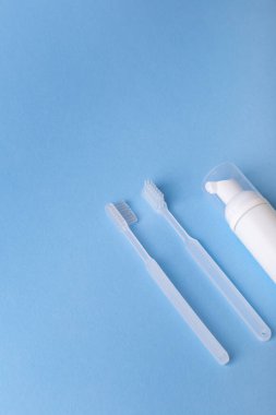 Mavi arka planda beyaz diş fırçası ve diş macunu var. Ağız bakımı, sakız ve diş sağlığı. Sabah rutini ve sağlık hizmetleri.