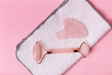 Yüz masajcısı ve pembe arka planda yüz havlusu. Güzellik ayinleri..