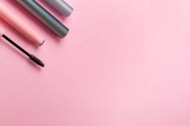 Yukarıdan pembe arka planda farklı türde rimel. Makyaj araçları.