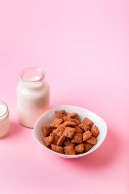 Kuru kahvaltı ve süt. Kuru, tatlı kahvaltı. Çikolatalı mısır yastıkları ve pembe arka planda süt. Hızlı ve besleyici bir kahvaltı. Pembe arkaplan.