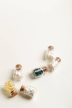Bej arka planda vitamin, mineral ve gıda takviyeleriyle dolu küçük cam kavanozlar. Vitamin, d3, a, e, b, c, magnezyum, çinko gibi vitamin ve mineraller içeren besin takviyeleri, haplar, tabletler ve kapsüller. Sağlıklı yaşam tarzı.