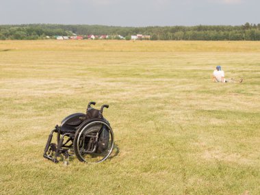 the wheelchair and the person sitting on the grass, Moscow regio clipart