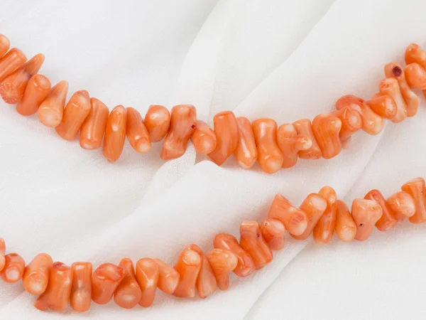 Bright coral beads on white cloth — Stock Photo, Image