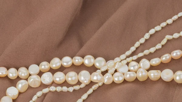 Pearl beads on brown cloth — Stock Photo, Image