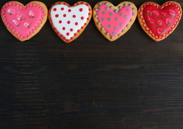Печенье в форме сердца с великолепными узорами королевской глазури выстроились на черном деревянном фоне