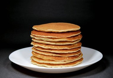 Beyaz tabakta servis edilen ev yapımı sade krepler, siyah arka planda izole edilmiş.