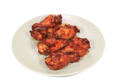 Beyaz bir tabakta servis edilen ızgara tavuk kanadı çubukları.