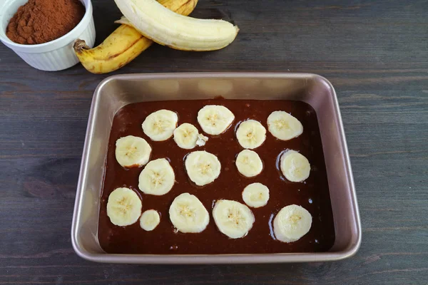 Homemade Dark Chocolate Banana Cake Batter in Cake Pan with Baking Ingredients on Wooden Table