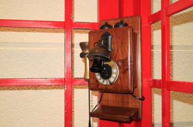 Kırmızı renkli telefon kulübesinde eski tarz ahşap telefon.