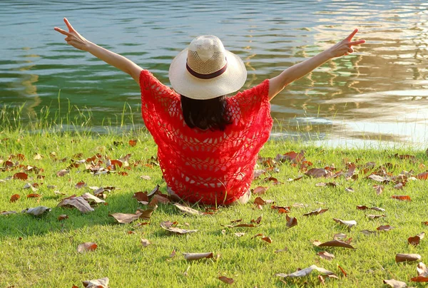 在湖边坐着V字牌的草帽高臂快乐女人 — 图库照片