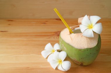 Tahta bir masada Frangipani çiçekleriyle taze hindistan cevizi suyu.