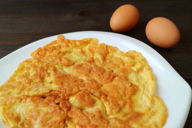 Koyu kahverengi ahşap masa üzerinde iki çiğ yumurta ile Tayland usulü omlet.