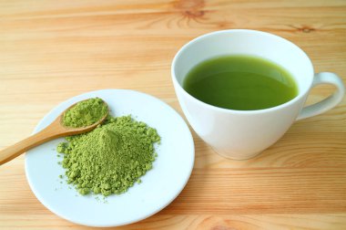 Bir tabak Matcha Tea Powder ve bir fincan sıcak kibrit yeşil çay.