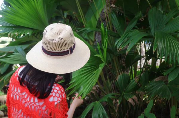 头戴宽边帽的妇女触摸巴拿马帽棕榈植物的叶子 — 图库照片