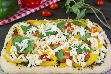 Renkli sağlıklı malzemelerle dolu pizza hamuru fırına konmaya hazır.