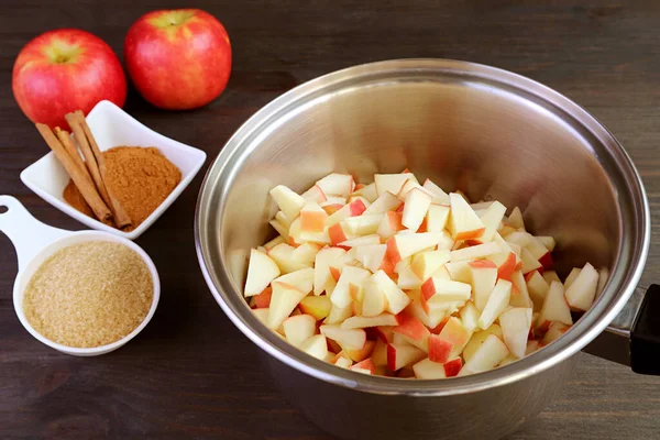 Pot of diced fresh apples with bowl of ingredients for making apple compote