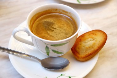 Cup of Hot Coffee with a Financier French Almond Mini Cake on White Table