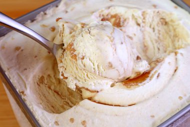Bir kaşık Scooping 'in yakın çekimi Enfes Karamelli Macadamia Fındık Dondurması Küvette