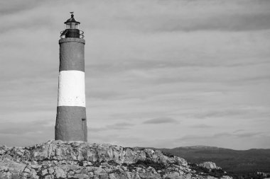 Tek renkli bulutlu gökyüzüne karşı kayalık adalardaki deniz feneri