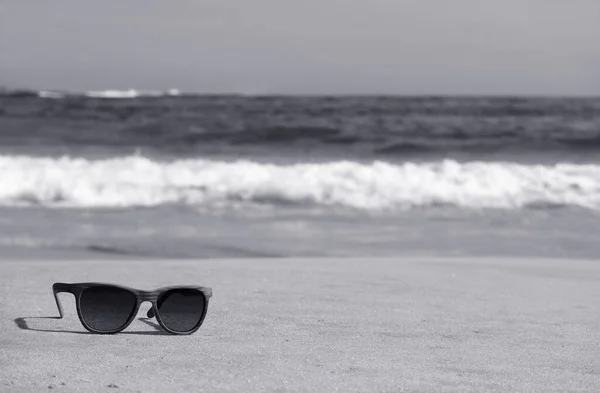 Monochromatyczny Obraz Okularów Przeciwsłonecznych Plaży Rozmytymi Falami Tle — Zdjęcie stockowe
