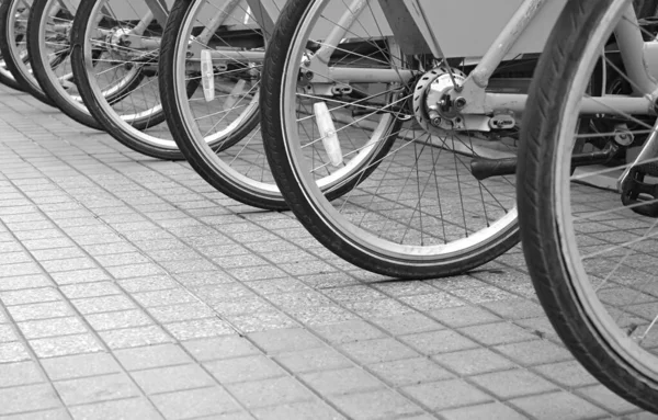環境に優しいコンセプトのためのダウンタウンサイドウォークの自転車ホイールの行 — ストック写真