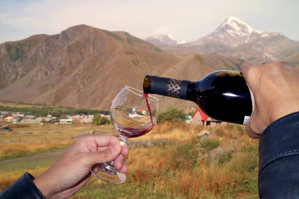 Mão Derramando Vinho Tinto Vinho Com Desfocado Kazbek Fundo Goergia — Fotografia de Stock