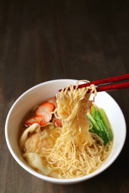 Yemek çubukları tarafından tutulan Çin yumurtalı eriştenin yakın çekimi.