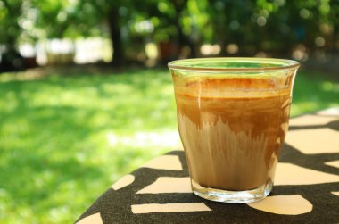 Bahçe masasında servis edilen bir bardak Kirli Latte Kahve.