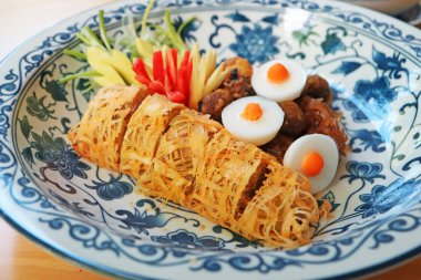 Stuffed sweet peppers with ground pork wrapped in fried lacy egg wrap, one of the essential side dishes of Khao Chae, a popular Thai summer refreshment