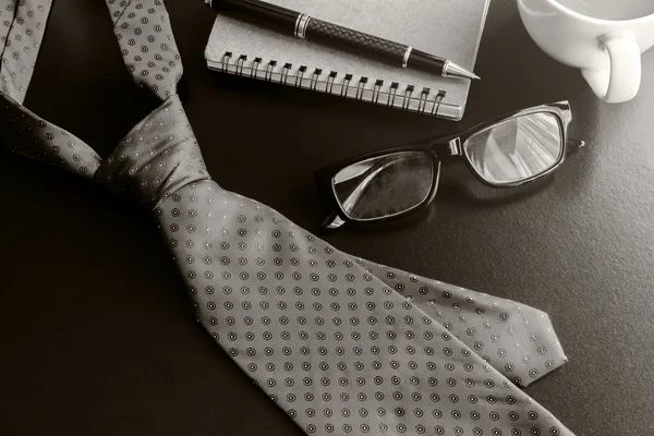 Necktie and cup of coffee on office desk — Stock Photo, Image