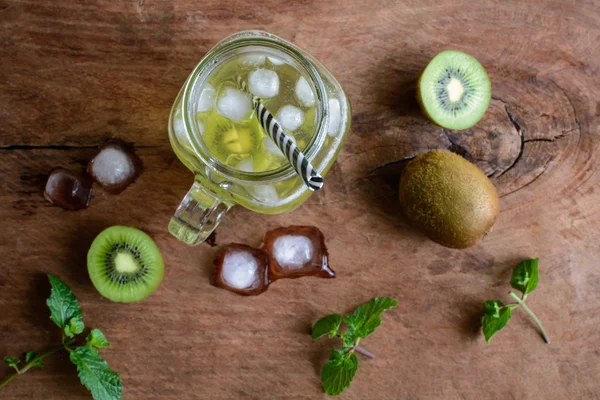 Soda kiwi y menta en un vaso sobre un fondo de madera . — Foto de Stock