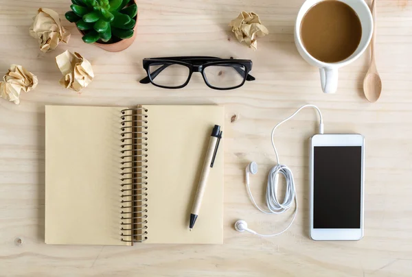 Carnet vierge avec écouteur et une tasse de café sur un bureau en bois — Photo