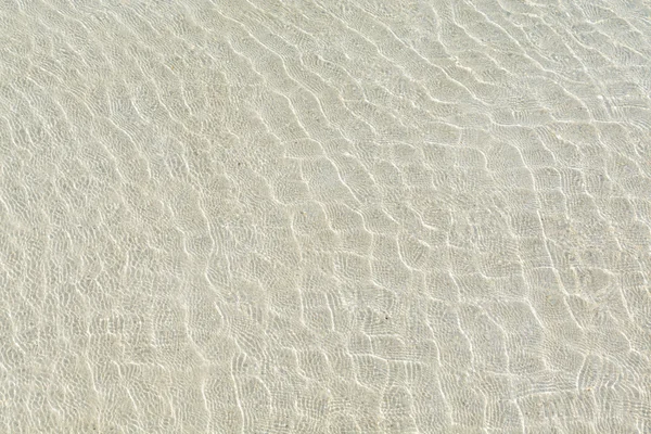 Transparant water rimpel en zonlicht schittering op witte zand — Stockfoto