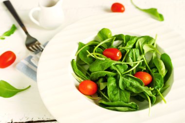 Beyaz ahşap zemin üzerinde kiraz domates ile roket salata