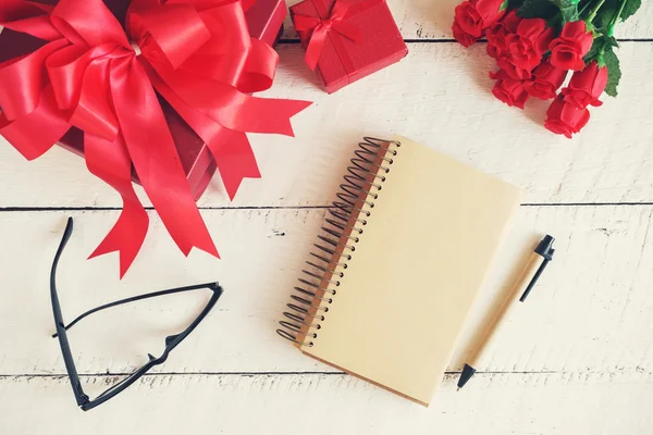 Blank notebook with red gift box and flower on white wooden back — Stock Photo, Image