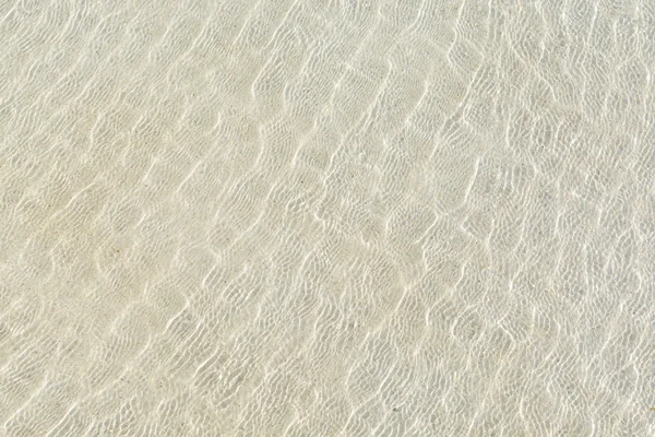 Transparent water ripple and sunlight glare on white sand — Stock Photo, Image