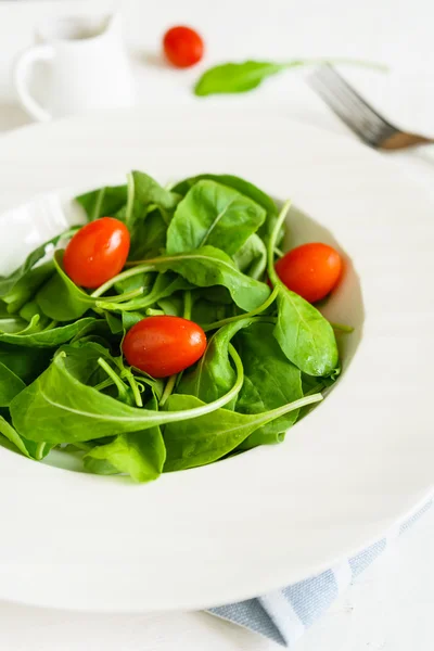 Insalata di rucola con pomodorini su sfondo bianco in legno — Foto Stock