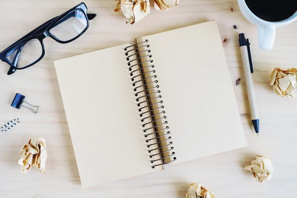 Bolas de papel arrugadas con anteojos y cuaderno en blanco — Foto de Stock