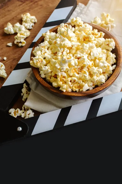 Movie clapper with popcorn on wooden background