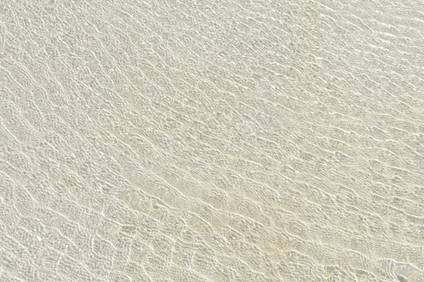 Ondulazione d'acqua trasparente e bagliore di luce solare su sabbia bianca — Foto Stock