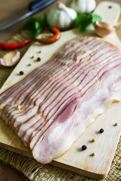 Skivor av bacon på trä bakgrund — Stockfoto