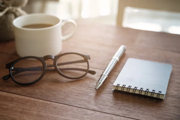 Cuaderno y taza de café con luz solar en la oficina del escritorio — Foto de Stock