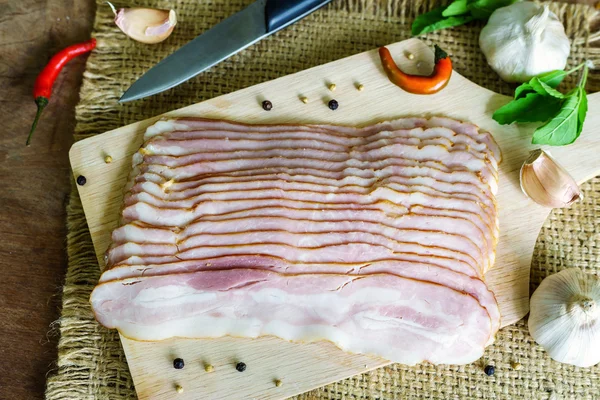 Skivor av bacon på trä bakgrund — Stockfoto