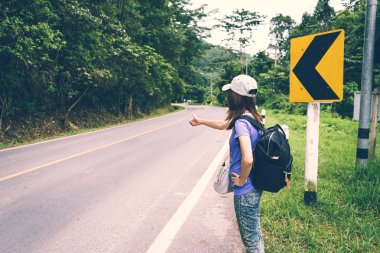 Şapka ve yolda otostop sırt çantası ile genç kız