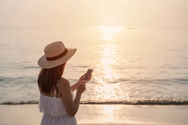 Νεαρή Γυναίκα Ταξιδιώτη Χρησιμοποιώντας Κινητό Τηλέφωνο Τροπική Παραλία Στο Ηλιοβασίλεμα — Φωτογραφία Αρχείου