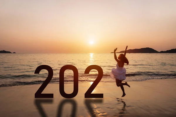 Genç bayan gezgin 2021 yılını gün batımında plajda kutluyor.