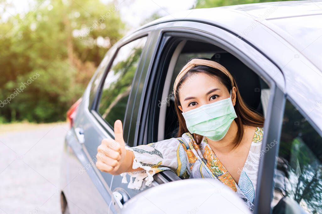The female driver wearing surgical mask felt confident and gesturing thumbs up while traveling